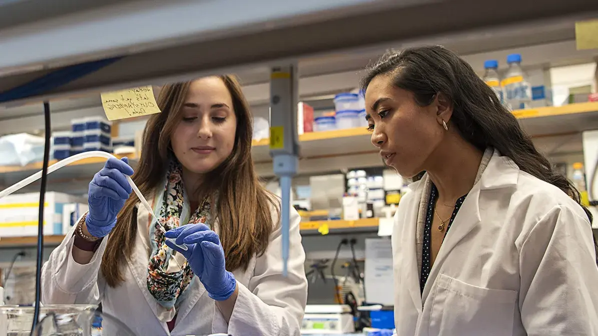 two female graduate researchers testing fluid in a tube